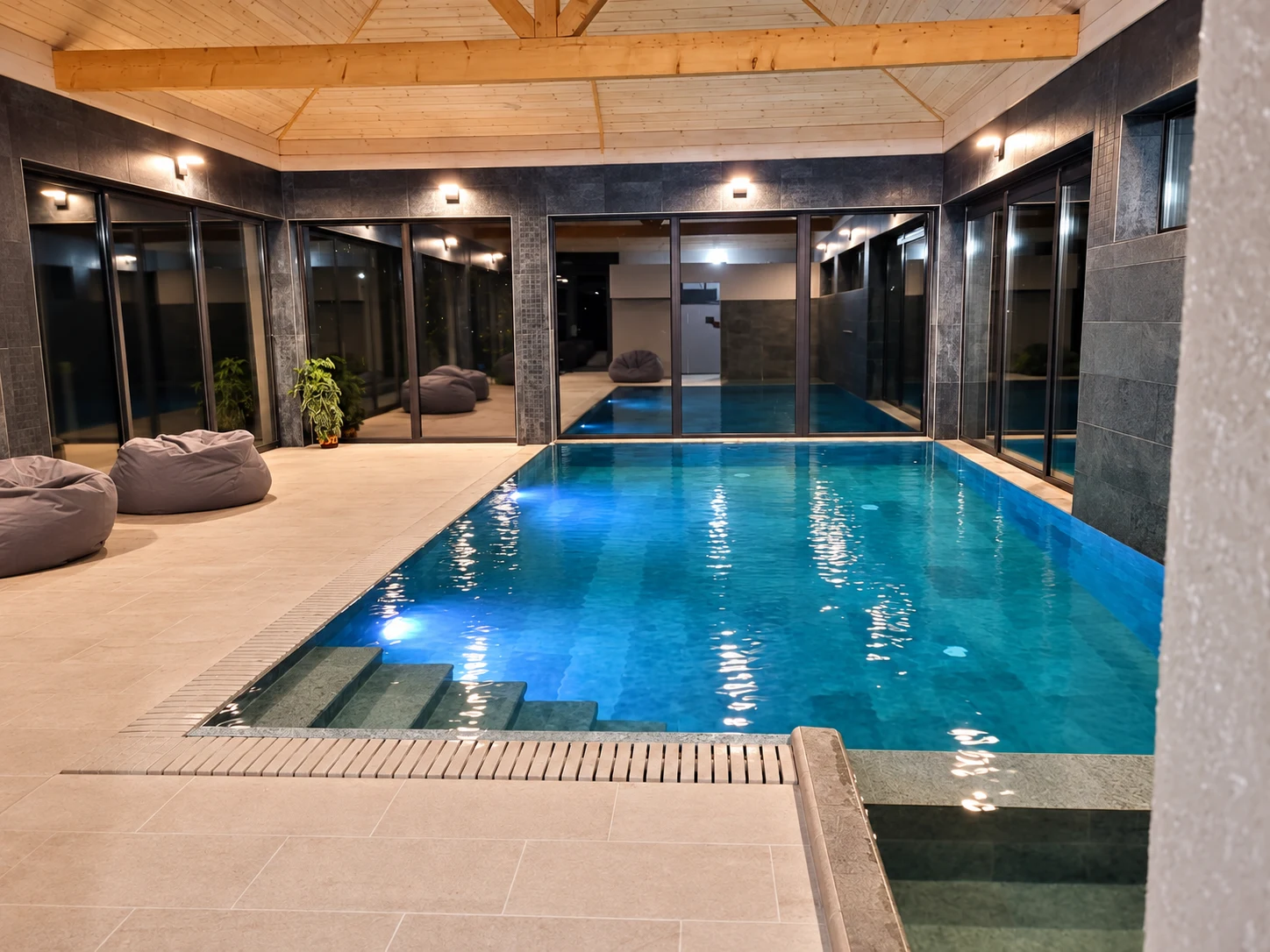 Piscina interioară cu șezlonguri și tavan din lemn